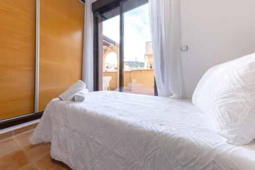 a white bed in a room with a window at Collados Experience Piscina y Parking in Águilas