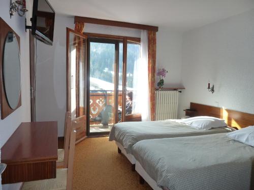 1 dormitorio con 2 camas y puerta corredera de cristal en Chalet-Hôtel du Borderan en La Clusaz