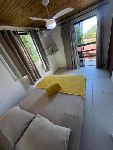 a bedroom with a bed with a yellow blanket on it at Pousada Mahara - Praia do Rosa in Imbituba