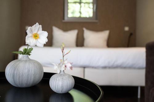 two white vases sitting on a table with a bed at De Swarte Ruijter in Holten