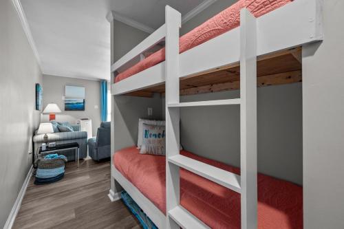 a bedroom with two bunk beds and a living room at Feel the Sea Breezes in North Topsail Beach