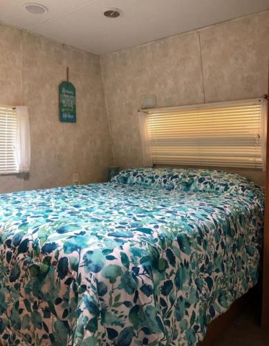 a bedroom with a bed with a floral bedspread at Cozy Camper NTB in North Topsail Beach