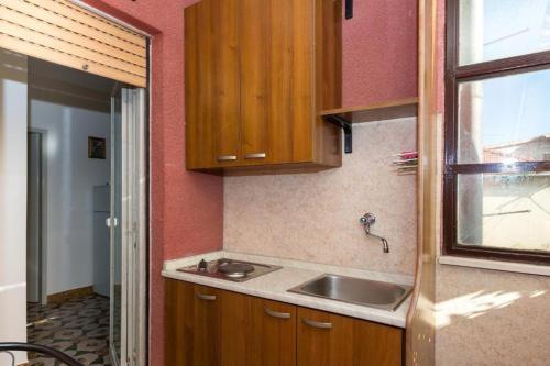 a kitchen with a sink and wooden cabinets and a window at Room Peričić in Strožanac