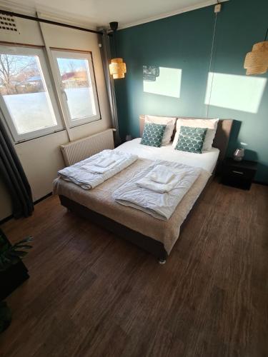 a bedroom with a bed and two windows at Het Dobbertje, charmant houten huisje in Sint Maartensvlotbrug