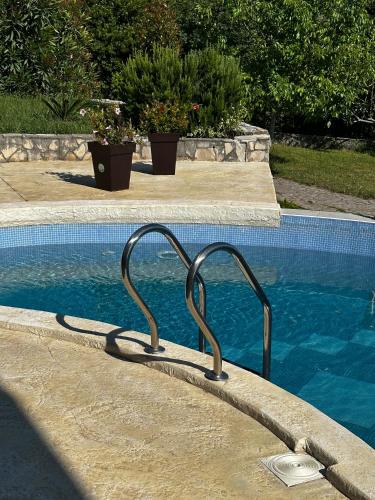 a swimming pool with a metal railing in the water at Villa 11 Infinity pool & garden in Dobra Voda
