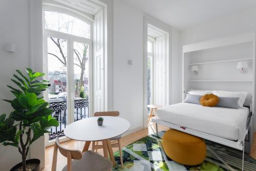 a white bedroom with a bed and a table at Casa dos Aromas - Heritage & Comfort - ApartHotel in Coimbra