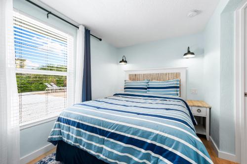 a bedroom with a blue and white striped bed and a window at Star Fish 3 Bed 2 bath POOL Walk to Beach in Sarasota