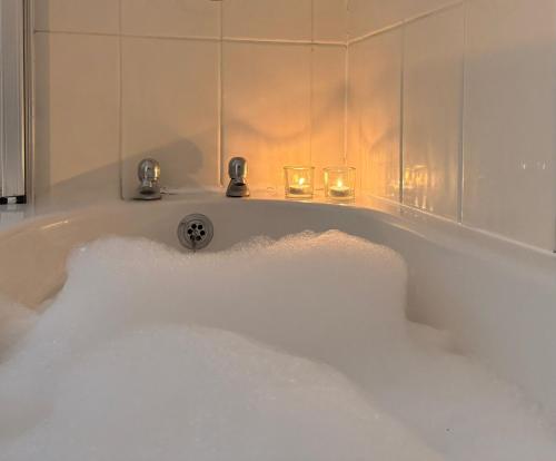 a bath tub filled with snow next to two wine glasses at Hindmarsh Apartment in Ashington