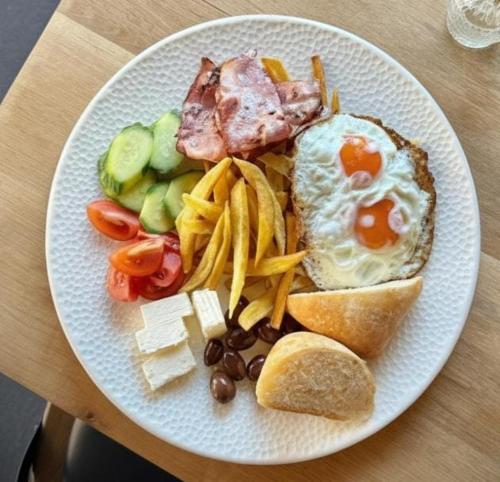 a plate of food with an egg sandwich and french fries at Campulung Chalets in Bughea de Sus