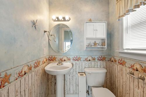 a bathroom with a sink and a toilet and a mirror at Sounds Like A Plan in Kill Devil Hills