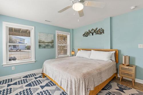 a bedroom with a bed and two windows at Sounds Like A Plan in Kill Devil Hills