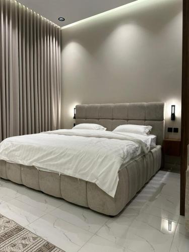 a bedroom with a large bed with white sheets at شقة اند هوم in Hail