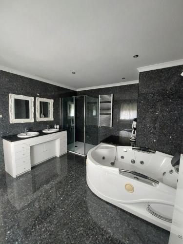 a large bathroom with a white tub and two sinks at Casa Flamingo in Viseu