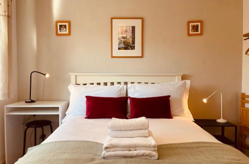 a bedroom with a white bed with red pillows at Peaceful 2 Bed Home with Parking Fast WIFI Easy Stress-Free Access to Bath in Bath