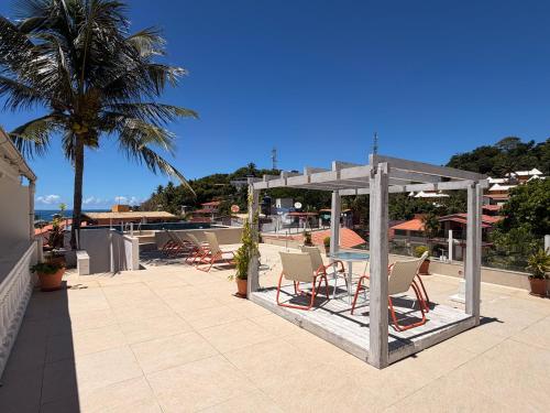 a patio with chairs and a pergola on a building at Piratas Do Morro Apartamento Praça in Morro de São Paulo
