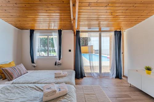 a bedroom with two beds and a large window at Wake up with the Sea Breeze- House with pool AP2 in Lavra