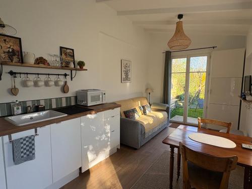 a kitchen and living room with a couch and a table at Gîte les violettes in Lagny