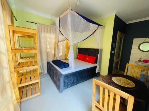a room with a bed with a canopy and a table at Giving Hands Homestay in Arusha