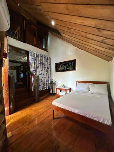 a bedroom with a bed and a wooden ceiling at Kuyas Tree House in Puerto Princesa City