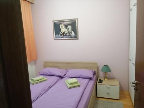 a bedroom with a purple bed with two towels on it at Apartman Foka Spa in Brzeće