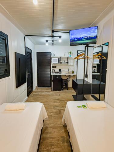 a room with two beds and a television on the wall at Studio Container - Conforto e Ótima Localização in Sinop
