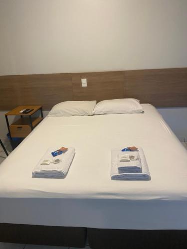 a large white bed with two towels on it at Hotel Sara - Ampere in Ampère