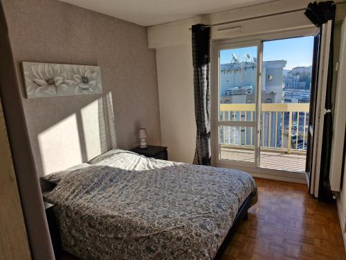 a bedroom with a bed and a large window at Appartement Hyper centre avec garage in Saint-Étienne