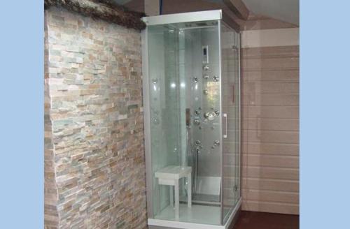 a glass shower in a room with a brick wall at La casa du clos in La Bernerie-en-Retz