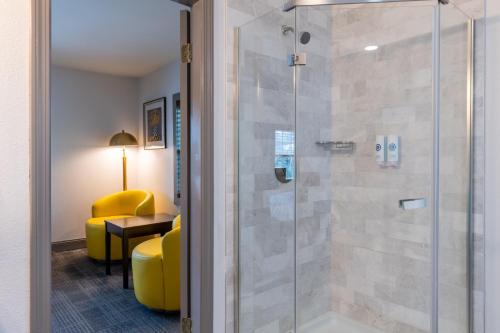 a bathroom with a glass shower with a yellow chair at Comfort Inn Rockland - Boston in Rockland
