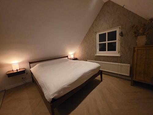 a bedroom with a bed and two lamps on two tables at Riekje in Lage Zwaluwe