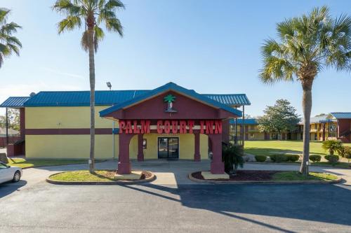 a small building with palm trees in a parking lot at OYO Hotel Pensacola I-10 & Hwy 29 in Pensacola