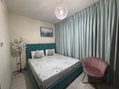 a bedroom with a bed and a pink chair at Belstay2 in Ras al Khaimah