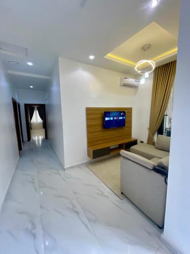 a living room with a couch and a tv on a wall at Luxury Four Bedroom Duplex in Asokoro Abuja in a Secure Estate with Fast WiFi & 24hours Electricity in Asokoro