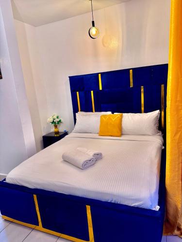a bed with a blue headboard and two towels on it at Sunstone Studio- Ngong Rd Near Junction Mall in Nairobi