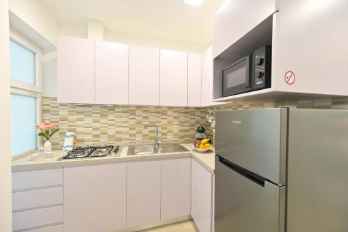 a kitchen with white cabinets and a refrigerator at Lucia Appartamenti in Ischia Town