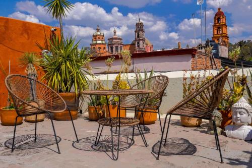 a patio with chairs and a table and potted plants at Casa H in San Miguel de Allende