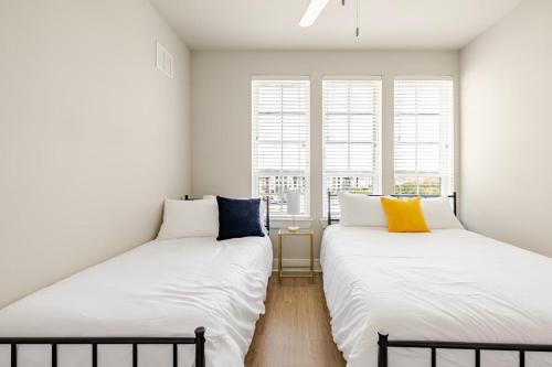 two beds in a room with white walls and windows at 1200sf 2bed 2bath Apt near Medical City, Toyota Stadium and The Ford Center in Frisco