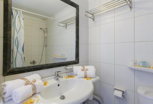 a white bathroom with a sink and a mirror at Hotel Tolo in Tolo