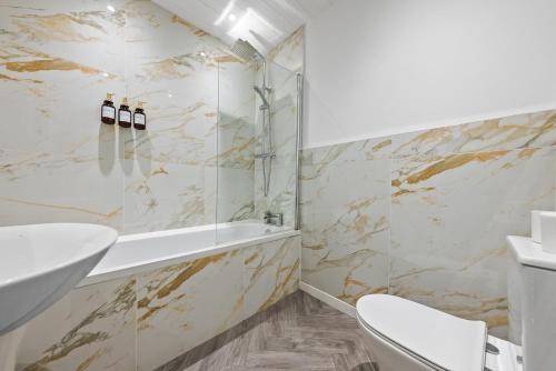 a bathroom with a tub and a toilet and a sink at Loch Lomond Retreat in Bonhill
