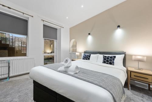 a bedroom with a large white bed and two windows at Loch Lomond Retreat in Bonhill
