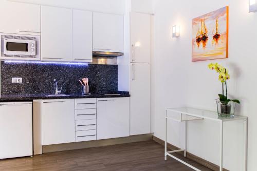 a kitchen with white cabinets and a counter top at BLUESEA Dimona Suites in Torremolinos