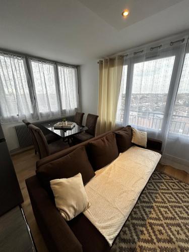 a living room with a couch and a table with windows at apartment with balcony in Ronchin