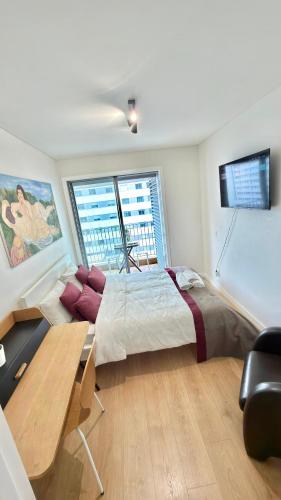 a bedroom with a bed and a desk and a window at Suíte aconchegante in Lisbon