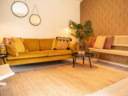a living room with a yellow couch and a table at Natuurhuisje met omheinde tuin hond welkom stijlvol ingericht StayatSas Julia in Epe