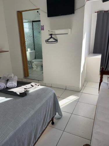 a bedroom with a bed and a bathroom with a toilet at Refugio Caiçara in Cananéia