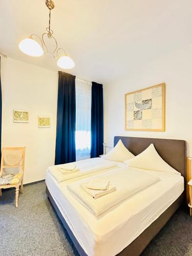 a bedroom with a large white bed with blue curtains at Hotel am Freihafen in Duisburg