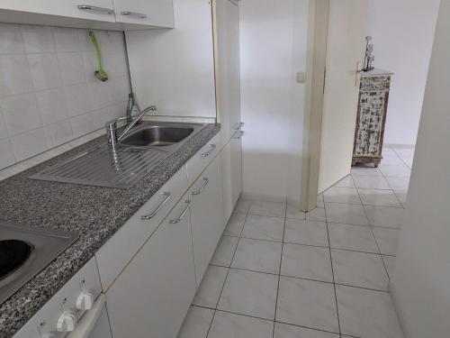 a white kitchen with a sink and a tiled floor at Charmanter Bungalow in Neubukow nahe der Ostsee in Neubukow