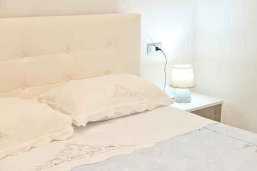 a white bed with two pillows and a lamp at Lucia's Apartments in Ischia Town