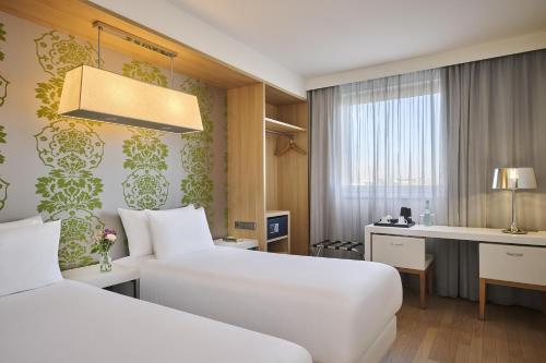 a hotel room with two beds and a desk at NH Ludwigsburg in Ludwigsburg