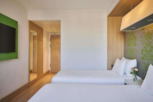 a hotel room with two beds and a tv at NH Ludwigsburg in Ludwigsburg